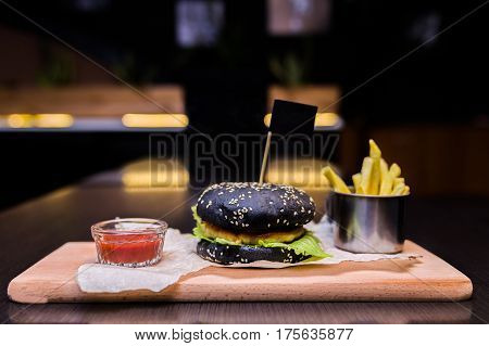 Burger on a wooden board with fries and sauce