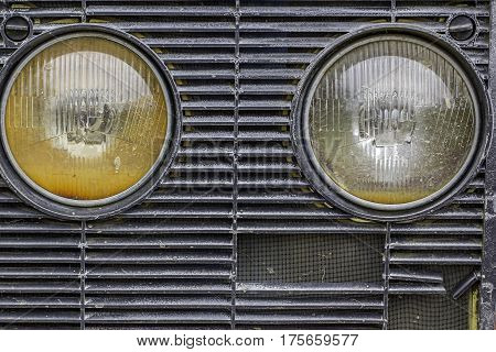 Head lamps on a farm vehicle grille. These orange and white lights are from a vintage tractor. Aesthetic abstract tranport related image.