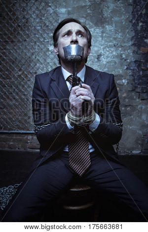 You wont get a ransom. Scared rich well dressed man telling his abductor about harming himself and holding up a gun while still being chained up