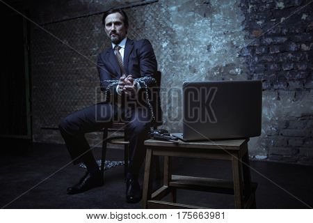 There is a weapon right here. Helpless scared rich man talking to someone using a webcam while being held hostage in some dark place
