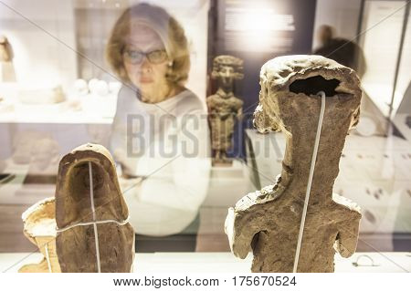 Madrid Spain - February 24 2017: Elder woman observing Carthaginian goddess figurines at National Archeological Museum of Madrid