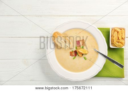 Delicious beer cheese soup with croutons and fried bacon on table