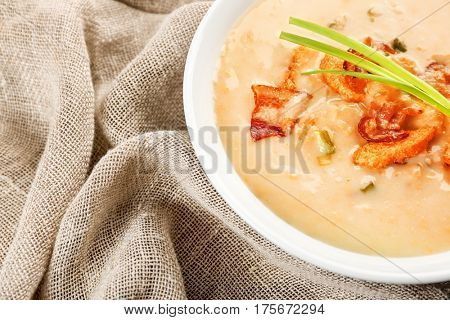 Delicious beer cheese soup with onion and fried bacon on table