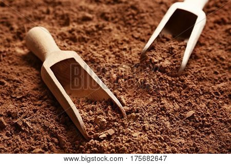 Wooden scoops on cocoa powder background