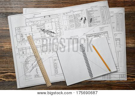 Open blueprints on wooden table background with a pencil, a ruler and compasses lying beside. Engineering and design. Construction projects. Planning.
