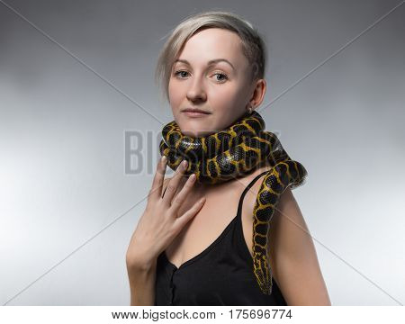 Woman and snake on her neck on gray background