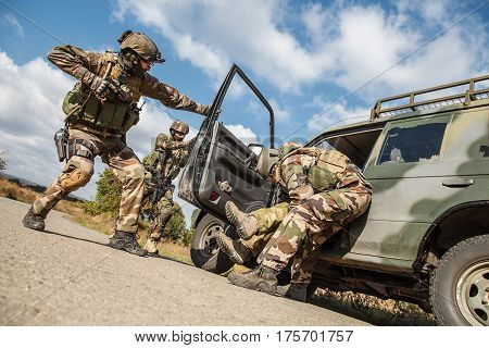 Squad of elite french paratroopers of 1st Marine Infantry Parachute Regiment RPIMA detaining terrorist in the car, low angle view