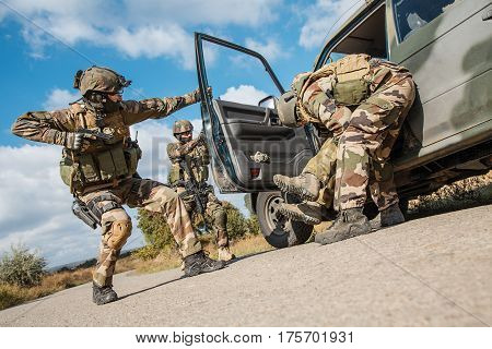 Squad of elite french paratroopers of 1st Marine Infantry Parachute Regiment RPIMA detaining terrorist in the car, low angle view