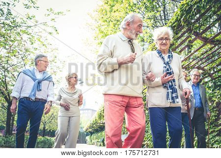 Group of senior people with some diseases walking outdoors - Mature group of friends spending time together
