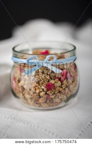 Cereal in jar with blue ribbon on white tablecloth.