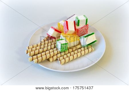 Multicolored marmalade sliced in pieces on a white plate - harm of sweet