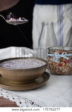 Milky soup with granola in brown bowl.