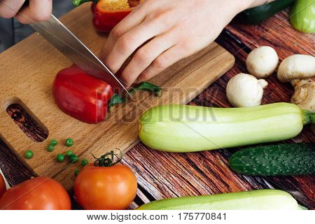 Cut zucchini on chopping board for cooking. Raw zucchini cut into slices before cooking, spices, chilli, herbs and olive oil on a wooden background.