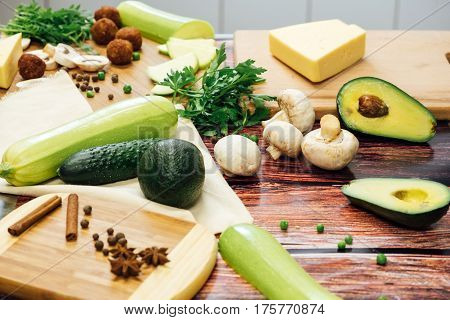 Cut zucchini on chopping board for cooking. Raw zucchini cut into slices before cooking, spices, chilli, herbs and olive oil on a wooden background.