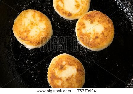 Beautiful pancakes made of cheese in a black frying pan. Cheesecakes. Pancakes curd. Pancakes fritters, a traditional dish of Russia and Ukraine.