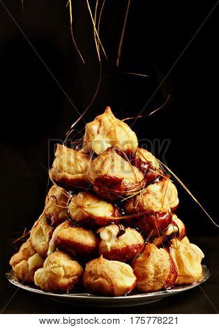 Cake Profiteroles With Caramel On Black Background.selective Focus. Flying Caramel