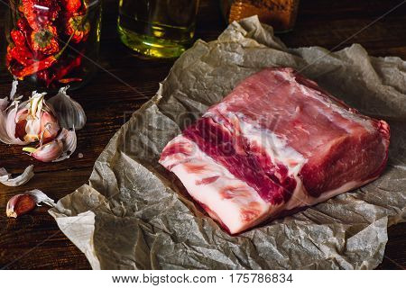 Raw Pork Loin on Kraft Paper. Some Ingredients on Background.