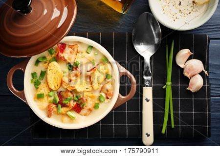 Delicious beer cheese soup with croutons and fried bacon on table
