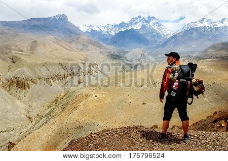 A traveler with a backpack in the Himalayan mountains looks at the gorge. Nepal. Kingdom of Upper Mustang.