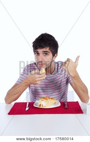 Jovem comendo um bolo com muito creme, gesticulando ok