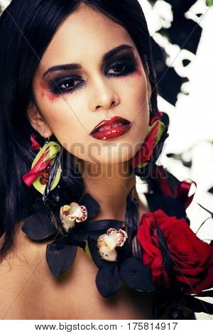 pretty brunette woman with rose jewelry, black and red, bright make up kike a vampire closeup red lips, halloween concept