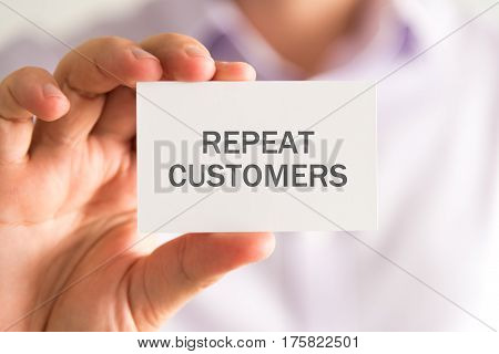 Businessman Holding A Card With Repeat Customers Message