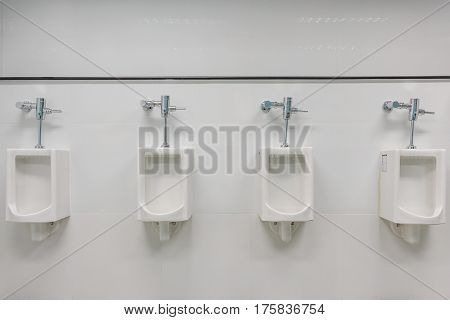 White urinals in clean men public toilet room interior.