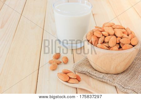 Almond milk in glass with almonds on wooden table Top view with copy space and text.