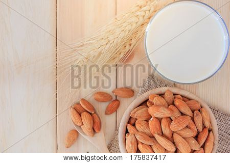 Almond milk in glass with almonds on wooden table Top view with copy space and text.