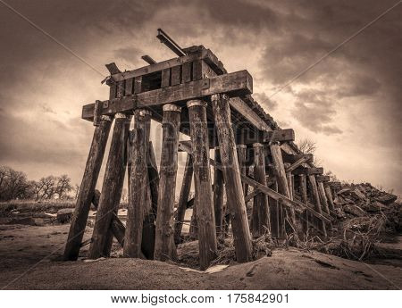 railroad timber trestle destroyed by river flooding - St Vrain Creek near Platteville, Colorado, sepia toning