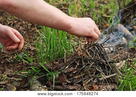 The man in the woods. Hands of a man who in the forest among the dry withered leaves kindle fire.