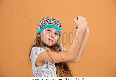 The face of sad teen girl in hat on brown studio background