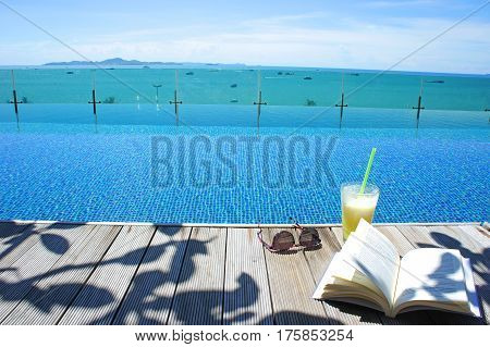 relax cocktail book sun glass at swimming pool with island view