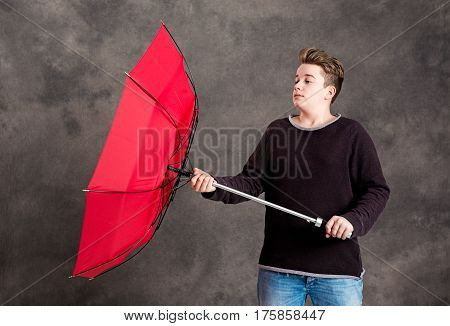 Teenager With Red Umbrella Standing In Strong Breeze
