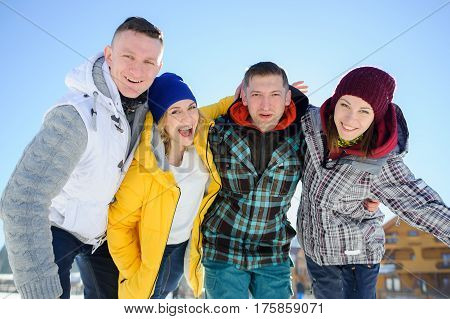 Cheerful group of friends posing for the camera. Two young men and two girl. All good mood. Friends are hugging and laughing merrily.