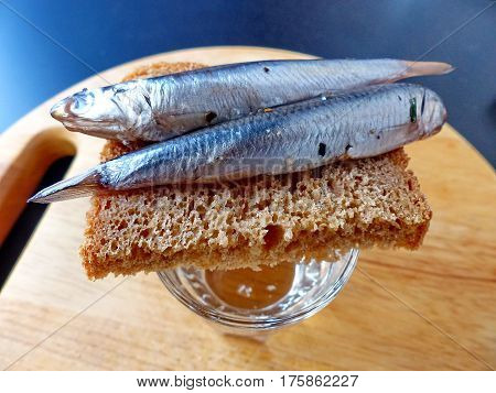 A bread, spicy salting anchovy  and a glass of vodka. Closeup. Gorgeous home appetizer under a glass of vodka. Natural food. Traditional Dishes of Russian Cuisine.