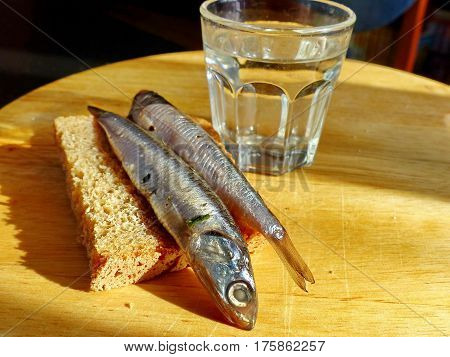A bread, spicy salting anchovy  and a glass of vodka. Closeup. Gorgeous home appetizer under a glass of vodka. Natural food. Traditional Dishes of Russian Cuisine.