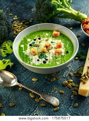 Dietary Broccoli smooth cream soup with sprinkle of sunflower seeds, parsley leaves and croutons on stone table