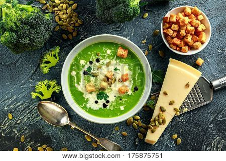 Dietary Broccoli smooth cream soup with sprinkle of sunflower seeds, parsley leaves and croutons on stone table