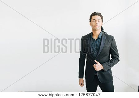 Happy young businessman in black suite and blue shirt standing over white background. Portrait of a handsome  boy. Color