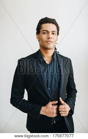 Happy young businessman in black suite and blue shirt standing over white background. Portrait of a handsome  boy. Color