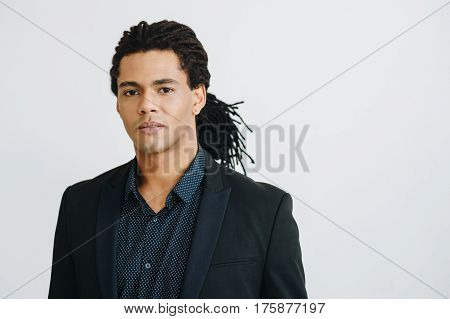 Happy young businessman in black suite and blue shirt standing over white background. Portrait of a handsome  boy. Color