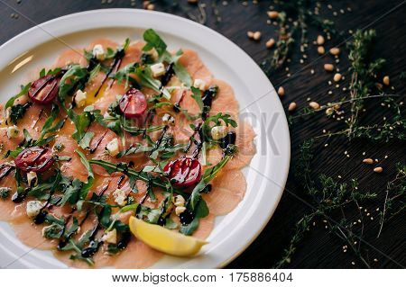 Salmon carpaccio with arugula leaves and sticky balsamic vinegar
