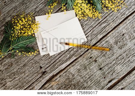 Vintage post cards mock up with yellow flowers mimosas and vintage pen ink on grey wooden background. Overhead view. Flat lay, top view, moke up