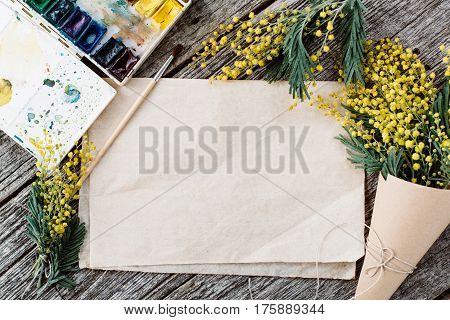 Make bouquet of mimosa. bandages twine and scissors on rustic wooden table, old paper for text and watercolors. Copy space for text. top view