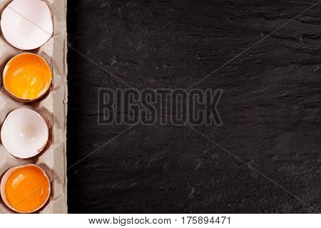 eggs in a tray on a dark stone background with copy space for your text. Top view.