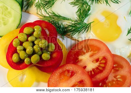 fried egg garnished with slices of juicy tomatoes and green peas