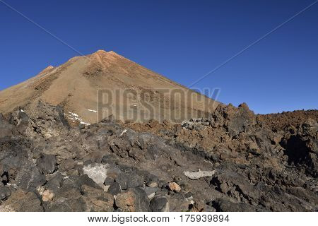 Teide top with lava stone in foreground and against a blue sky picture from Tenerife Spain.