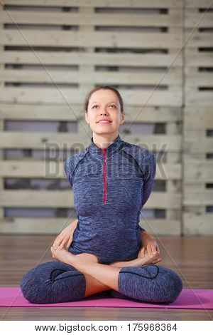 Portrait of sport girl doing yoga exercise on pink yoga maet in gym. Blue sportwear. Sport concept. Health lifestyle.
