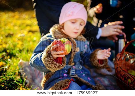Girl Sitting On The Grass With An Apple In His Hand